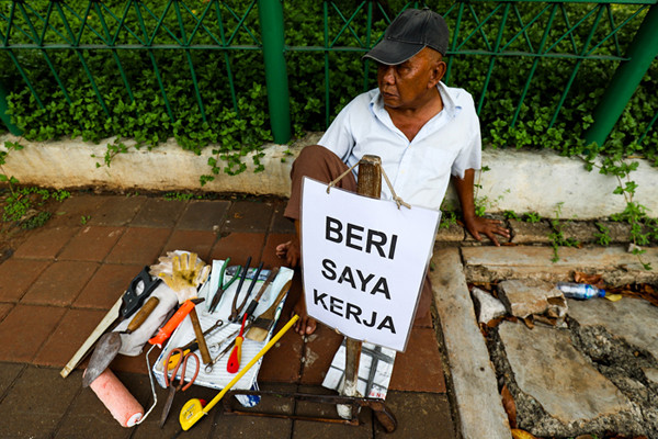 Seorang bapak berprofesi sebagai buruh tukang bangunan menunggu seseorang untuk mengajaknya bekerja di Kawasan Jakarta Pusat, Kamis (19/8/2021).