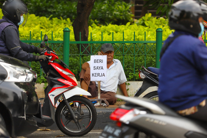 Seorang bapak berprofesi sebagai buruh tukang bangunan menunggu seseorang untuk mengajaknya bekerja di Kawasan Jakarta Pusat, Kamis (19/8/2021).