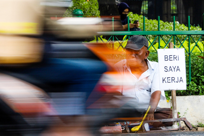 Seorang bapak berprofesi sebagai buruh tukang bangunan menunggu seseorang untuk mengajaknya bekerja di Kawasan Jakarta Pusat, Kamis (19/8/2021).