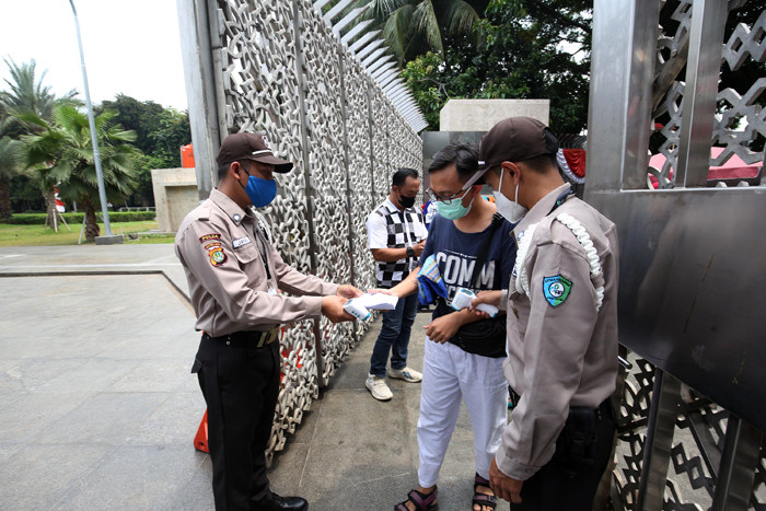 Petugas keamanan mengecek suhu badan warga yang akan menunaikan shalat Jumat di Masjid Istiqlal, Jakarta, Jumat (20/8/2021).