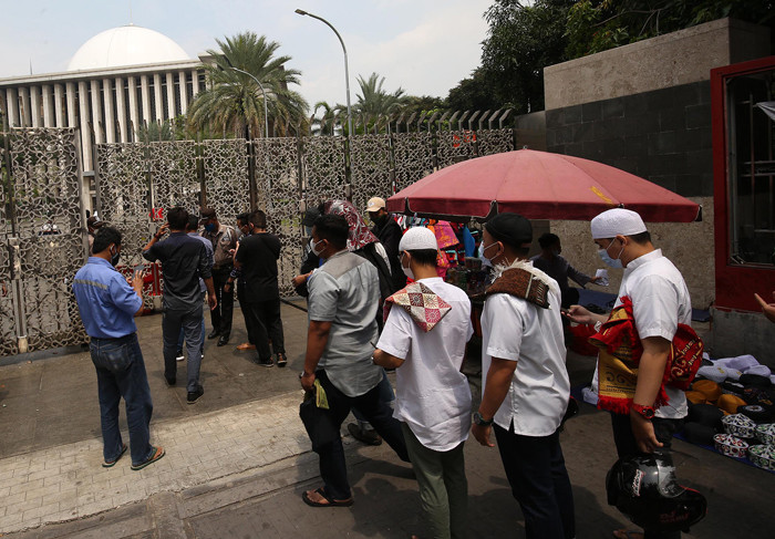 Petugas keamanan mengecek suhu badan warga yang akan menunaikan shalat Jumat di Masjid Istiqlal, Jakarta, Jumat (20/8/2021).
