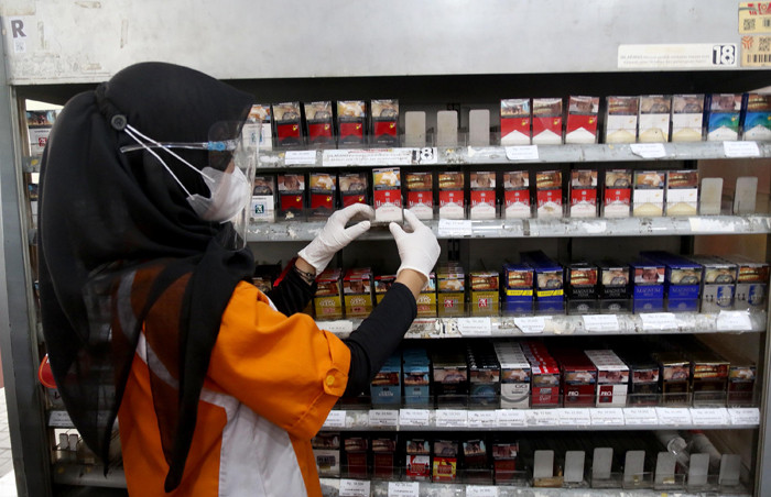 Pedagang menunjukkan bungkus rokok bercukai di Jakarta, Sabtu (21/8/2021).