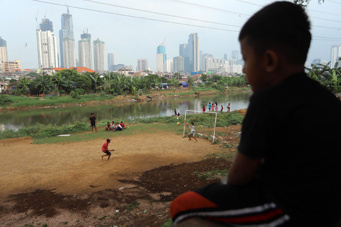 Sejumlah anak bermain sepak bola di bantaran sungai Kanal Banjir Barat, Sabtu (21/8/2021).