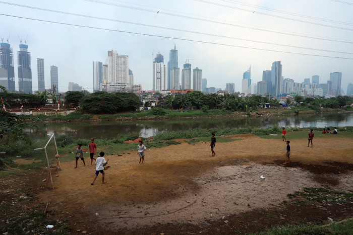Sejumlah anak bermain sepak bola di bantaran sungai Kanal Banjir Barat, Sabtu (21/8/2021).