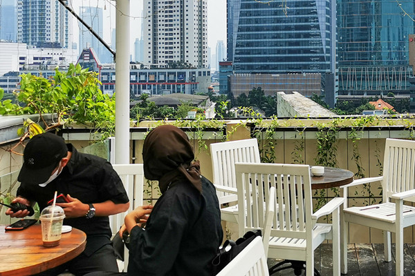 Pengunjung saat menikmati suasana di sebuah resto hotel dengan pemandangan gedung-gedung bertingkat di Jakarta Selatan, Minggu (22/8/2021).