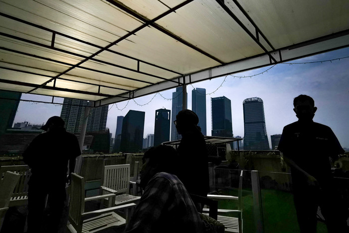 Pengunjung saat menikmati suasana di sebuah resto hotel dengan pemandangan gedung-gedung bertingkat di Jakarta Selatan, Minggu (22/8/2021).