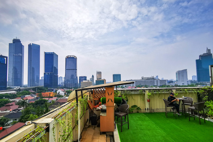 Pengunjung saat menikmati suasana di sebuah resto hotel dengan pemandangan gedung-gedung bertingkat di Jakarta Selatan, Minggu (22/8/2021).