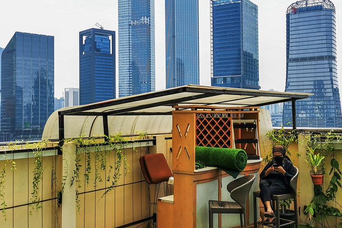 Pengunjung saat menikmati suasana di sebuah resto hotel dengan pemandangan gedung-gedung bertingkat di Jakarta Selatan, Minggu (22/8/2021).