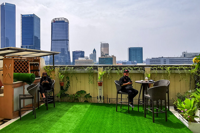 Pengunjung saat menikmati suasana di sebuah resto hotel dengan pemandangan gedung-gedung bertingkat di Jakarta Selatan, Minggu (22/8/2021).