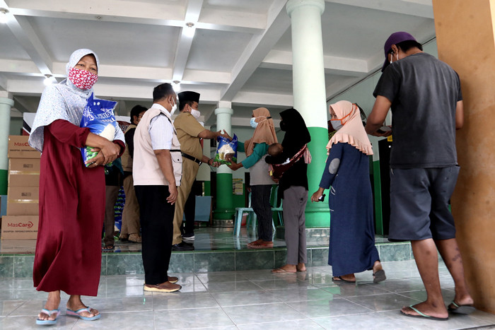 Warga mengambil jatah beras di Desa Tambak Sumur, Waru, Sidoarjo, Jawa Timur, Senin (23/8/2021).