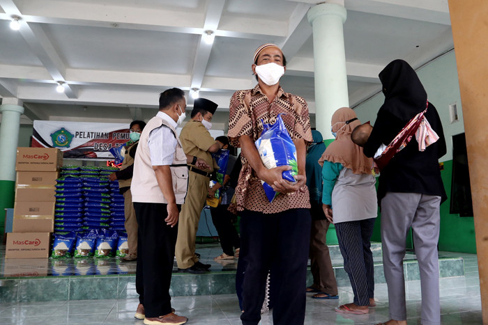 Warga mengambil jatah beras di Desa Tambak Sumur, Waru, Sidoarjo, Jawa Timur, Senin (23/8/2021).