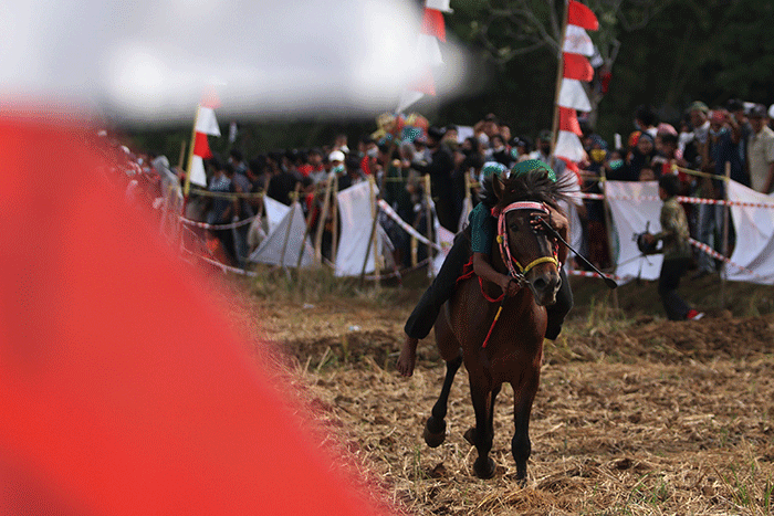 Sejumlah warga menyaksikan pacuan kuda tradisional di Kecamatan Simbang, Desa Tanete, Kabupaten Maros, Rabu (25/8/2021).
