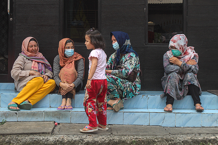 Seorang pencari suaka asal Afghanistan bermain telepon genggam di dalam tenda di trotoar jalan kawasan Kebon Sirih, Jakarta Pusat, Jumat (27/8/2021).