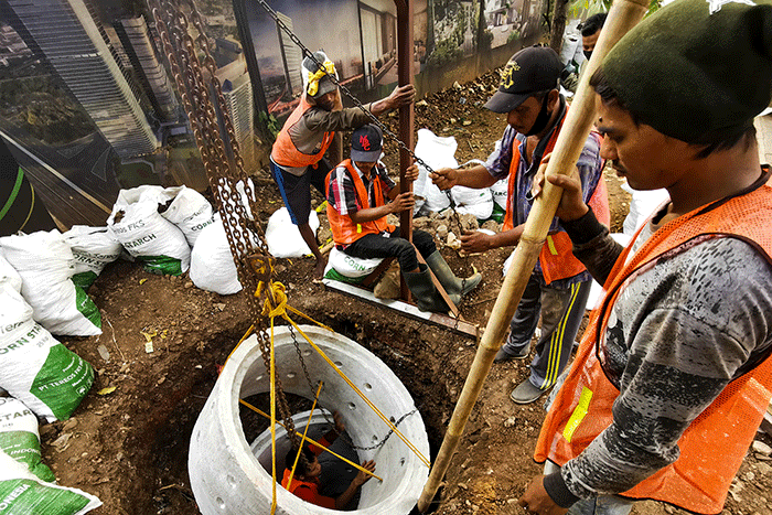Pekerja sedang menyelesaikan pembuatan drainase vertikal atau sumur resapan di trotoar jalan Gatot Subroto, Jakarta Selatan, Jumat (27/8/2021).