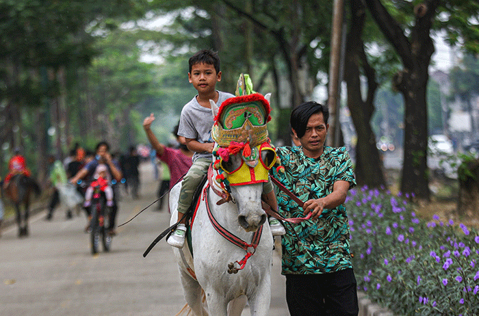 Seorang anak menunggangi kuda yang disewakan di kawasan Banjir Kanal Timur, Jakarta, Minggu (29/8/2021).