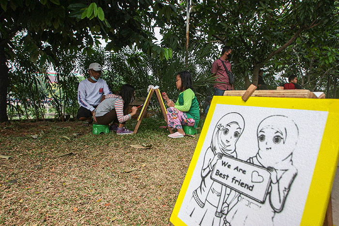 Seorang anak menunjukan hasil karya mewarnai miliknya di kawasan Banjir Kanal Timur, Jakarta, Minggu (29/8/2021).