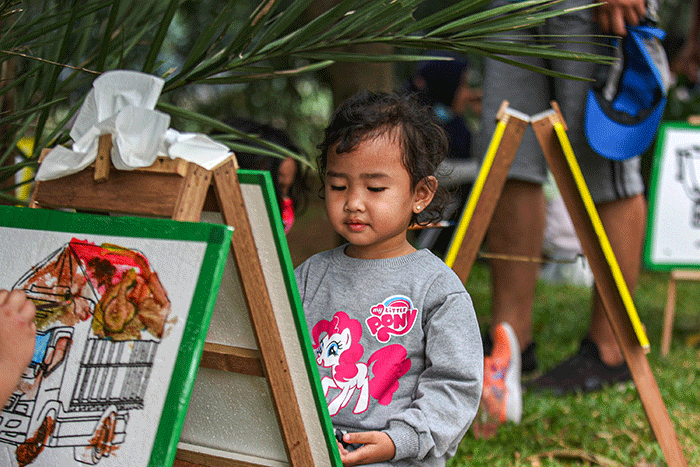 Seorang anak menunjukan hasil karya mewarnai miliknya di kawasan Banjir Kanal Timur, Jakarta, Minggu (29/8/2021).