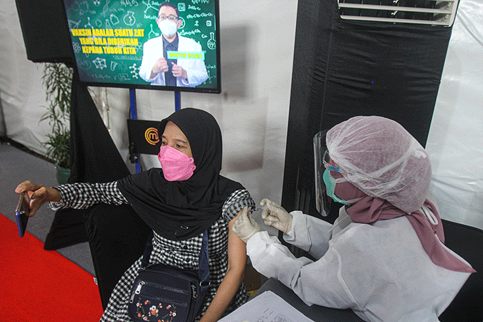 Vaksinator saat menyuntikan vaksin Covid-19 kepada warga di Sentra Vaksinasi MNC Studios, Kebon Jeruk, Jakarta Barat, Senin (30/8/2021).