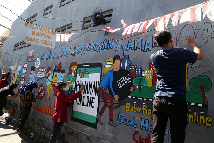 Mahasiswa Universitas Muhammadiyah Surabaya yang tergabung dalam Himpunan Mahasiswa Perbankan Syariah membuat mural edukasi di Surabaya, Senin (6/9/2021).