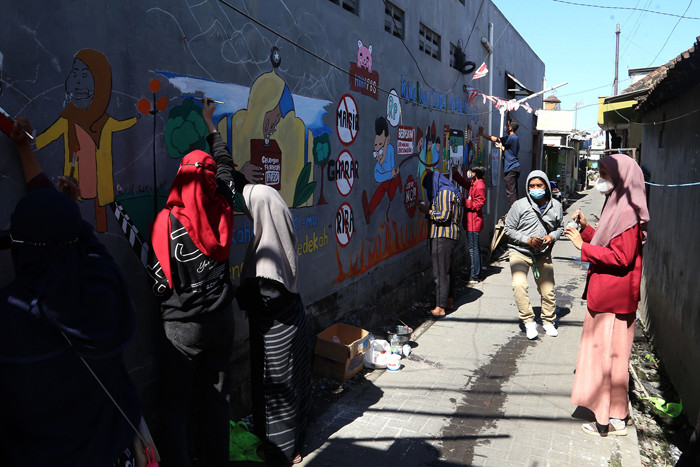 Mahasiswa Universitas Muhammadiyah Surabaya yang tergabung dalam Himpunan Mahasiswa Perbankan Syariah membuat mural edukasi di Surabaya, Senin (6/9/2021).