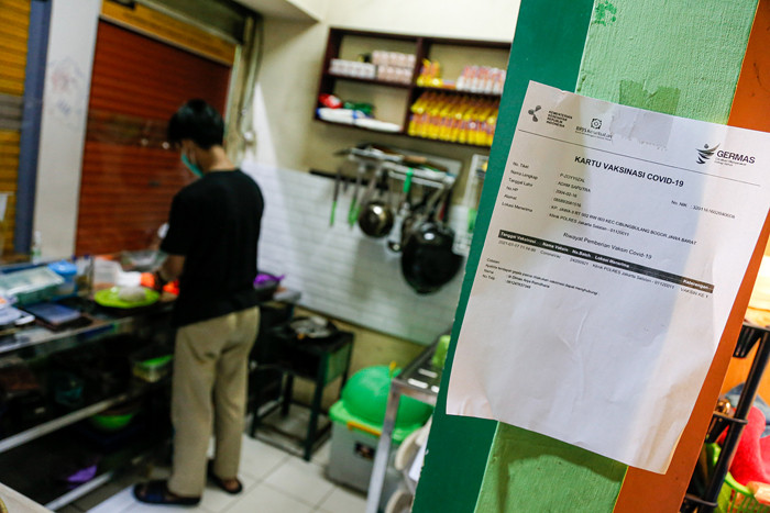Pedagang menjaga toko sembakonya yang dipasang stiker sertifikat vaksin Covid-19 di Pasar Santa, Jakarta Selatan, Senin (6/9/2021).