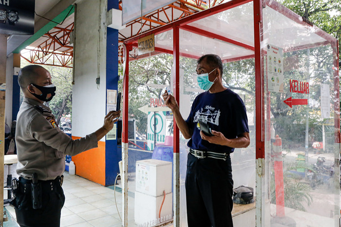 Pedagang menjaga toko sembakonya yang dipasang stiker sertifikat vaksin Covid-19 di Pasar Santa, Jakarta Selatan, Senin (6/9/2021).