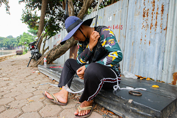 Warga saat memancing menggunakan alat pancing yang sudah dimodifikasi dengan jaring di Setu Pedongkelan, Depok, Jawa Barat, Minggu (12/9/2021).