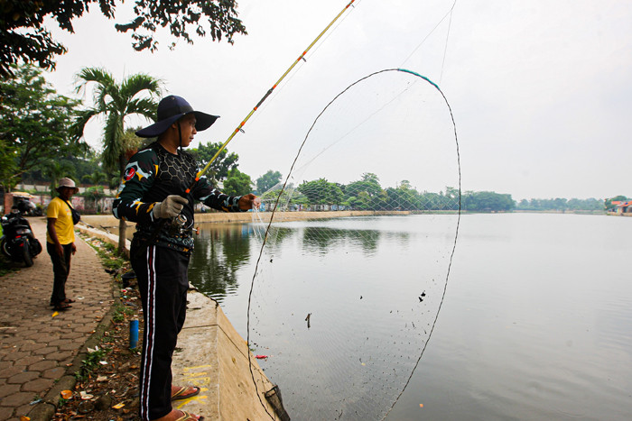 Warga saat memancing menggunakan alat pancing yang sudah dimodifikasi dengan jaring di Setu Pedongkelan, Depok, Jawa Barat, Minggu (12/9/2021).