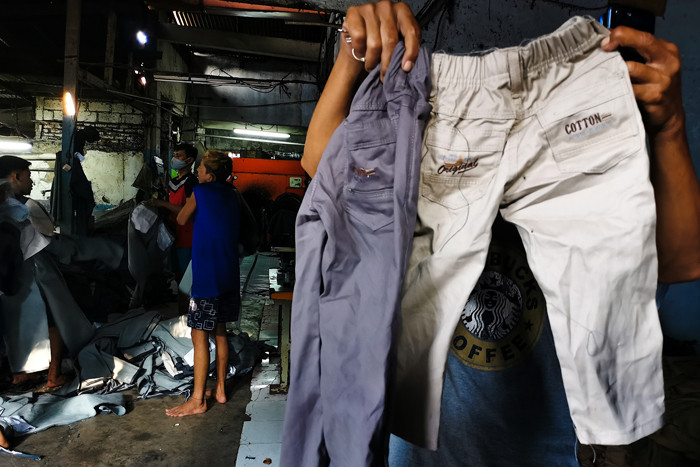 Pekerja sedang menyelesaikan pencucian celana garmen dan konveksi di kawasan Jakarta Barat, Jumat (17/9/2021).