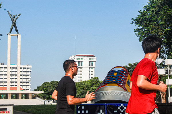 Warga melintasi dua tugu sepatu di Taman Lapangan Banteng, Jakarta Pusat, Jumat (17/9/2021).