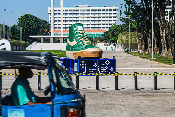 Warga melintasi dua tugu sepatu di Taman Lapangan Banteng, Jakarta Pusat, Jumat (17/9/2021).