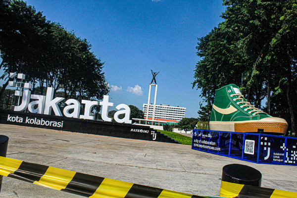 Warga melintasi dua tugu sepatu di Taman Lapangan Banteng, Jakarta Pusat, Jumat (17/9/2021).