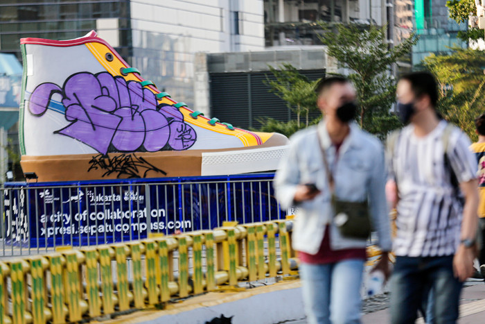 Warga berfoto dengan latar belakang Tugu Sepatu di Stasiun BNI City, Jakarta Pusat, Sabtu (18/9/2021).