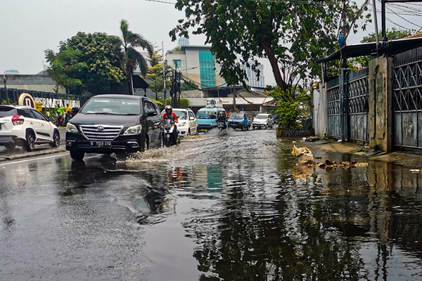 Kendaraan saat melintasi genangan air di jalan raya Kebayoran Lama, Jakarta Selatan, Minggu (19/9/2021).