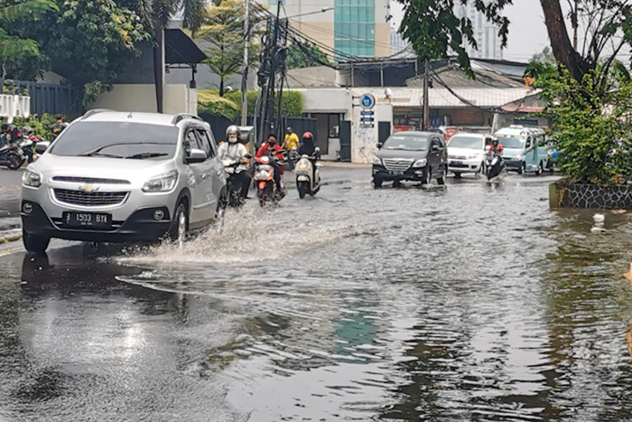Kendaraan saat melintasi genangan air di jalan raya Kebayoran Lama, Jakarta Selatan, Minggu (19/9/2021).