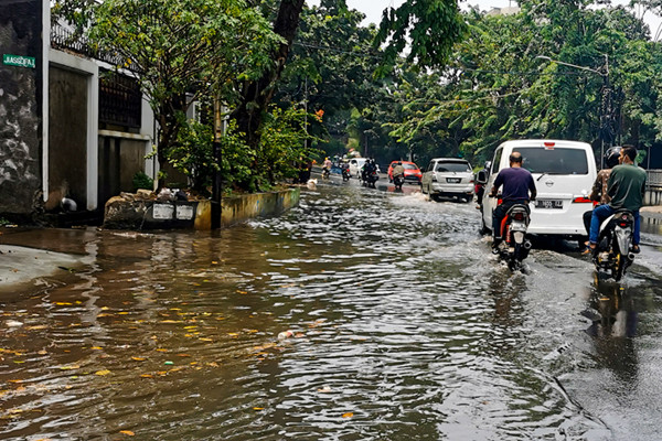 Kendaraan saat melintasi genangan air di jalan raya Kebayoran Lama, Jakarta Selatan, Minggu (19/9/2021).