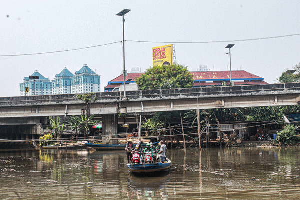 Sejumlah pengendara motor menggunakan jasa perahu eretan di kawasan Kali Angke, Kapuk, Jakarta Barat, Senin (20/9/2021).