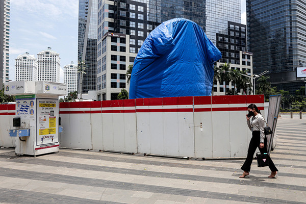 Warga melintas di dekat proyek pembangunan Tugu Sepeda di jalur pedestrian Jalan Jendral Sudirman, Jakarta Pusat, Kamis (23/9/2021).