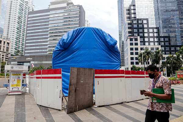 Warga melintas di dekat proyek pembangunan Tugu Sepeda di jalur pedestrian Jalan Jendral Sudirman, Jakarta Pusat, Kamis (23/9/2021).