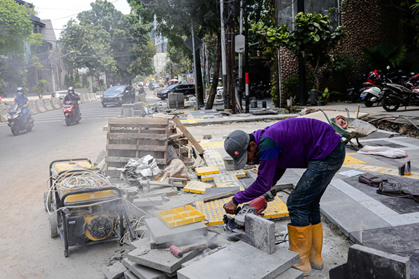 Pekerja menyelesaikan proyek revitalisasi trotoar di Jalan Senopati, Jakarta Selatan, Jumat (24/9/2021).