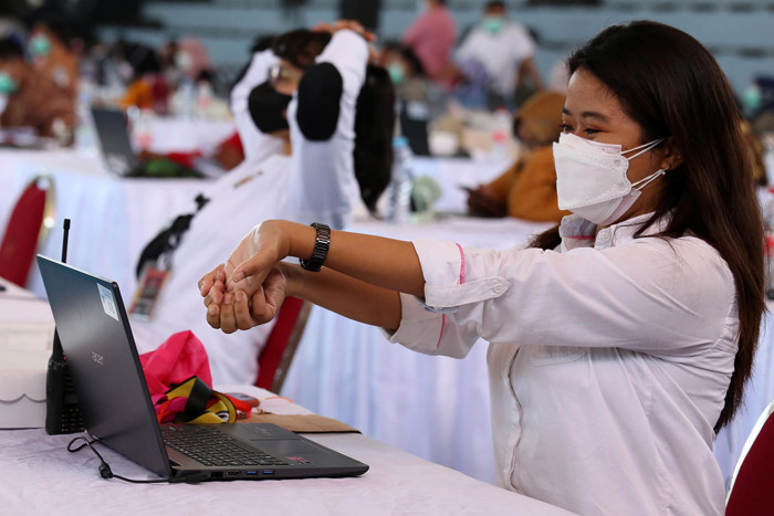 Petugas entry data peserta vaksin melakukan senam tangan untuk melenturkan ketegangan ketika menjalankan tugas di Surabaya, Jawa Timur, Kamis (30/9/2021).