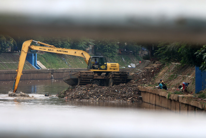 Petugas Dinas SDA Provinsi DKI Jakarta menggunakan alat berat saat mengeruk lumpur di aliran sungai Ciliwung, kampung Melayu, Jakarta, Senin (4/10/2021).