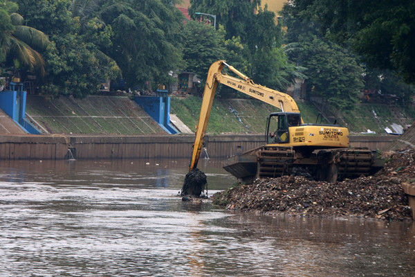 Petugas Dinas SDA Provinsi DKI Jakarta menggunakan alat berat saat mengeruk lumpur di aliran sungai Ciliwung, kampung Melayu, Jakarta, Senin (4/10/2021).