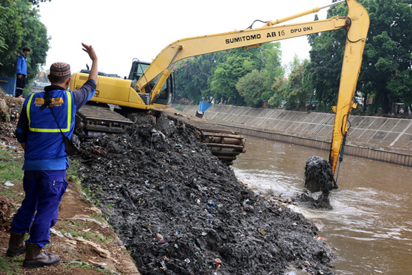 Petugas Dinas SDA Provinsi DKI Jakarta menggunakan alat berat saat mengeruk lumpur di aliran sungai Ciliwung, kampung Melayu, Jakarta, Senin (4/10/2021).