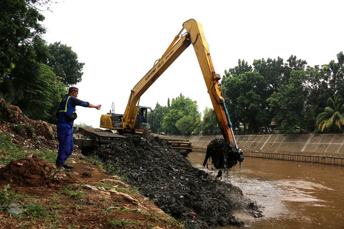 Petugas Dinas SDA Provinsi DKI Jakarta menggunakan alat berat saat mengeruk lumpur di aliran sungai Ciliwung, kampung Melayu, Jakarta, Senin (4/10/2021).