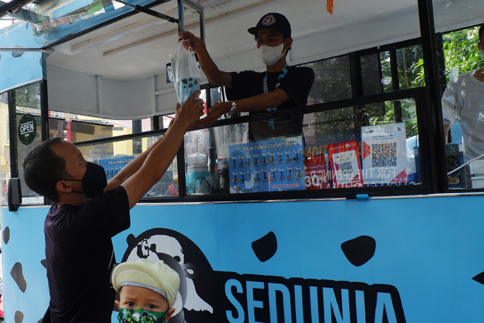 Pembeli Susu Sedunia melakukan pembayaran secara digital atas gerobak UMKM di kawasan Bendungan Hilir, Jakarta Pusat, Minggu (3/10/2021).