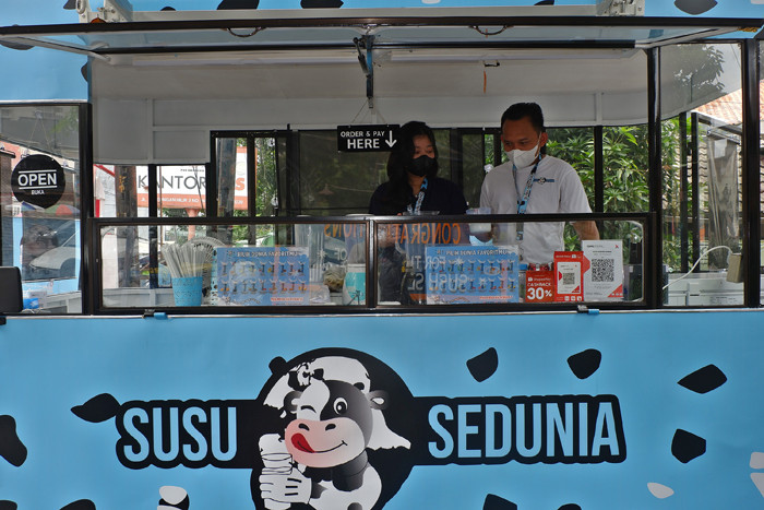 Pembeli Susu Sedunia melakukan pembayaran secara digital atas gerobak UMKM di kawasan Bendungan Hilir, Jakarta Pusat, Minggu (3/10/2021).
