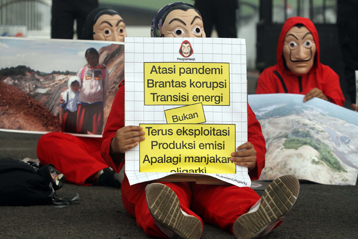 Sejumlah aktivis mengenakan kostum film Money Heist membentangkan poster saat melakukan aksi di depan Gedung DPR, Jakarta, Senin, (4/10/2021).