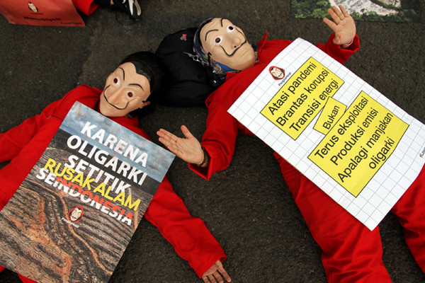 Sejumlah aktivis mengenakan kostum film Money Heist membentangkan poster saat melakukan aksi di depan Gedung DPR, Jakarta, Senin, (4/10/2021).