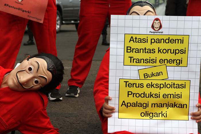 Sejumlah aktivis mengenakan kostum film Money Heist membentangkan poster saat melakukan aksi di depan Gedung DPR, Jakarta, Senin, (4/10/2021).